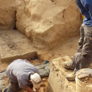 Archaeologist excavating an artifact while another archaeologist observes