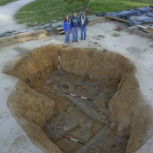 Archaeologists stand around an excavation unit