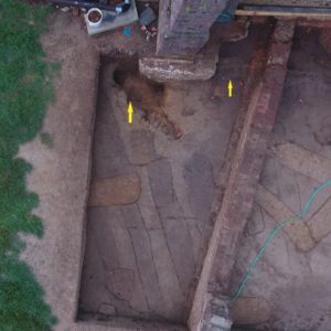 Notated excavated features next to brick church wall