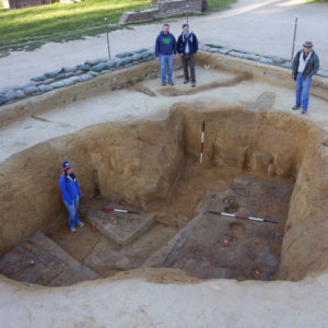 Archaeologists standing in and around an excavation unit