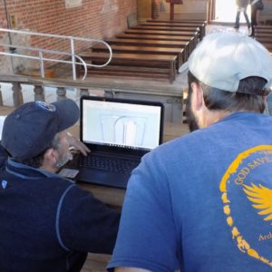 Archaeologists examine church design model on a computer screen