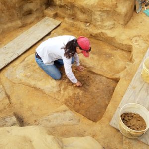 Archaeologist troweling in an excavation unit