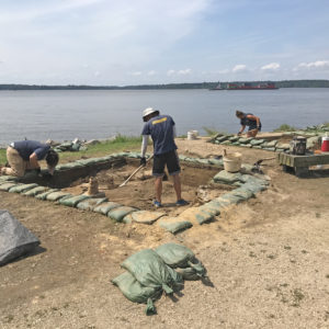 archaeologists excavating next to a riverbank