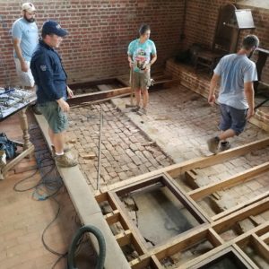 Staff and students stand in brick church chancel prior to excavations