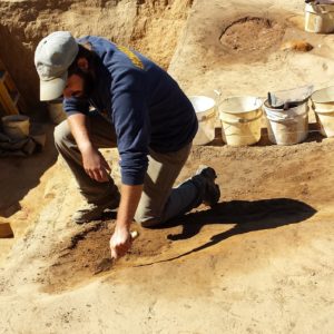 Archaeologist troweling in an excavation unit