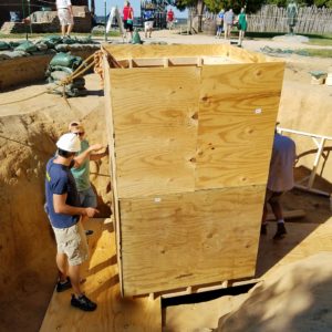 Archaeologists putting wooden well ring into excavated well