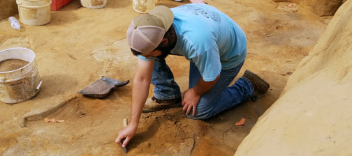 Archaeologist troweling in an excavation unit