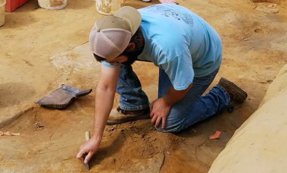 Archaeologist troweling in an excavation unit