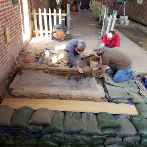 Conservators discussing a tombstone in the floor of a brick church