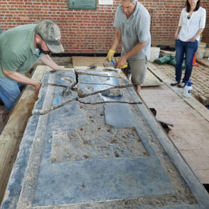 Conservators arrange tombstone fragments on cart