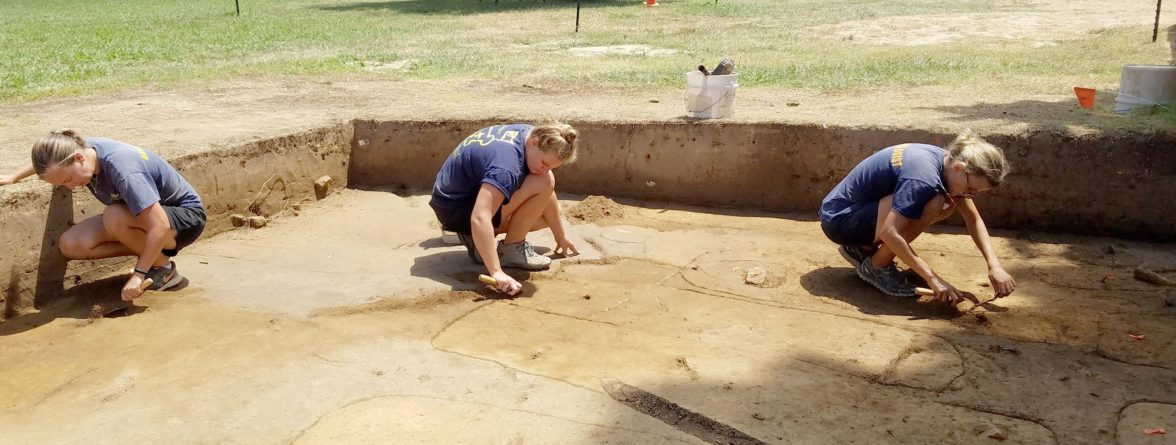 Archaeologists excavating above outlined grave shafts