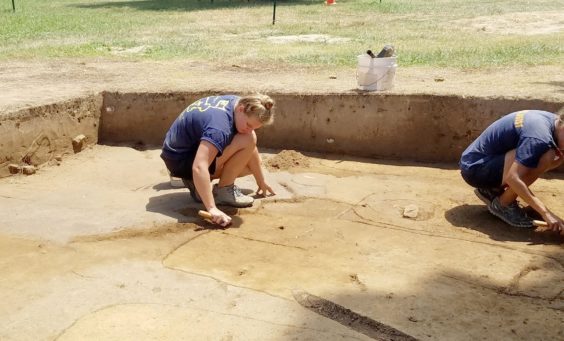 Archaeologists excavating above outlined grave shafts