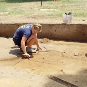 Three archaeologists excavating in unit