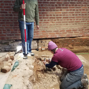 Archaeologist excavates brick and dirt church floor