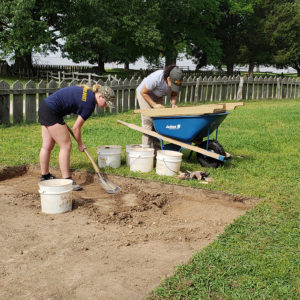 Two archaeologists shovel dirt