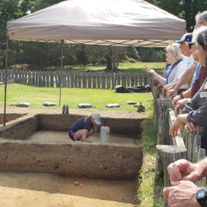 Archaeologist talks to group behind a fence