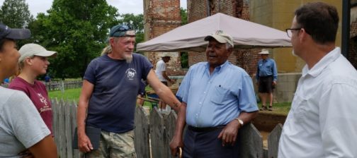 Man talking to group in front of brick ruins