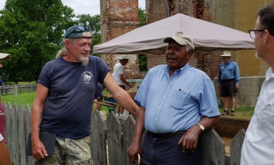 Man talking to group in front of brick ruins