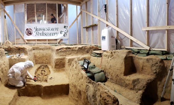 Archaeologists in Tyvek suits excavate and record burial