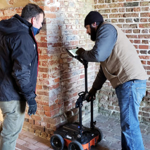 Two staff members examine data on the screen of a mobile ground penetrating radar unit