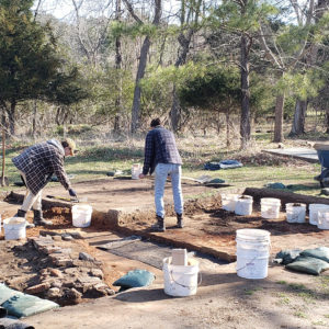 Archaeologists excavating with buckets and wheelbarrows