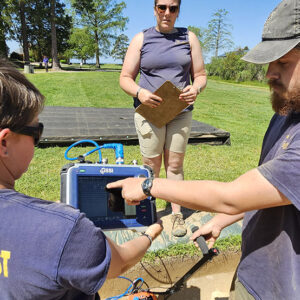 Archaeologists Caitlin Delmas, Hannah Barch, and Josh Barber perform a ground-penetrating radar (GPR) survey in one of the excavation squares in the north field.