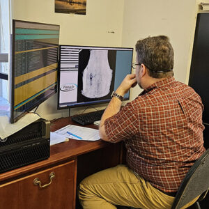 Senior Conservator Dr. Chris Wilkins examines a new X-ray of the breastplate taken out of the Archaearium for conservation. X-rays help inform the course of conservation by showing the density of the metal across the entirety of the artifact. A thin portion may mean extra care is taken in that area or that a different course of conservation is used to avoid damaging what's left of the original metal.