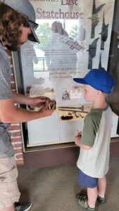 Field school student Richard Fallon shares the grenade fragment with a visitor inside the Archaearium.