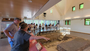 St. Mary's City Manager of Archaeological Services Ruth Mitchell gives a tour of the St. John's Site Museum to staff and field school students.