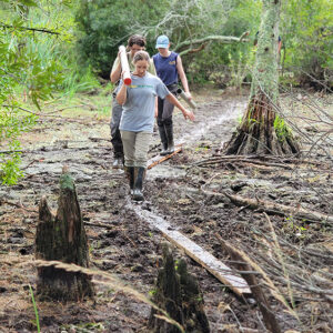 Staff Archaeologist Natalie Reid and field school students Lexy Marcuson and Julia Womersley-Jackman carry a soil sample back to dry land for transport to the lab of TerraSearch Geophysical's Dr. David Leslie.