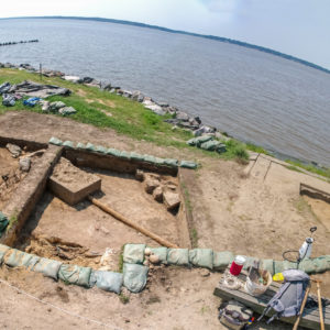 aerial view of archaeologists working in an excavation unit next to a riverbank