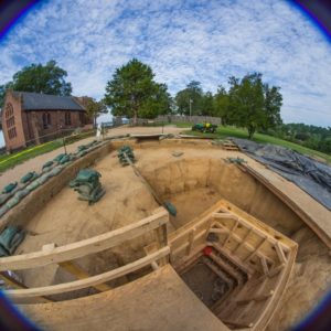 Fisheye view of well lined with wooden siding and church in background