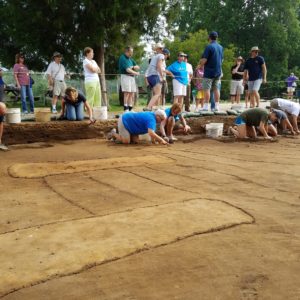 Students excavating planting furrows while archaeologist gives tour in the background