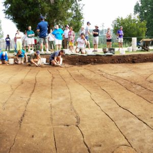 Visitors watch students excavating planting furrows