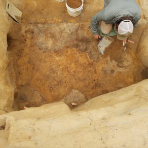 Archaeologist troweling in an excavation unit