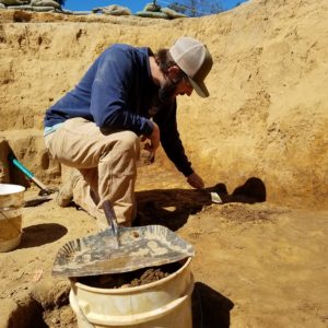 Archaeologist troweling in an excavation unit