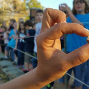 Lead die being held up to camera with group of children in the background