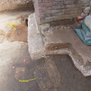 Postholes next to brick church wall