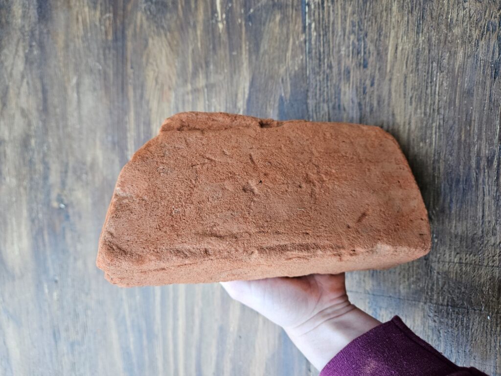 A large brick with parallel lines running along the long edges of the brick.