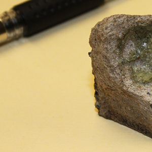 crucible fragment next to a pen for scale