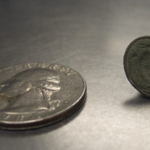 Seal with bird design next to a quarter for scale