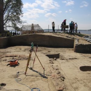 Transit standing in an excavation unit with outlined features