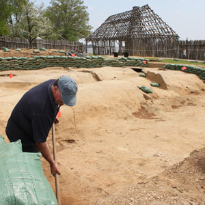 archaeologist shoveling in a large excavation area