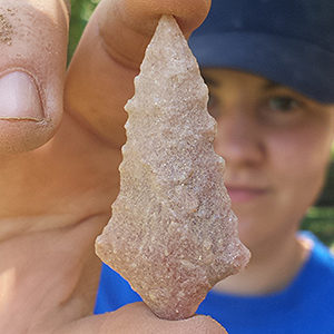 Excavator holding pink quartzite projectile point