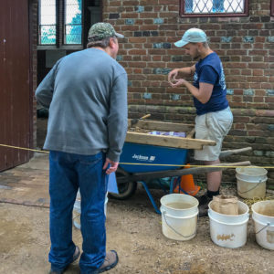 Archaeologist shows visitor artifact found in screen