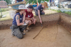 Archaeological Field Technician Ren Willis, field school student Hope Clark, and Staff Archaeologist Natalie Reid examine a burial discovered just south of the Archaearium.