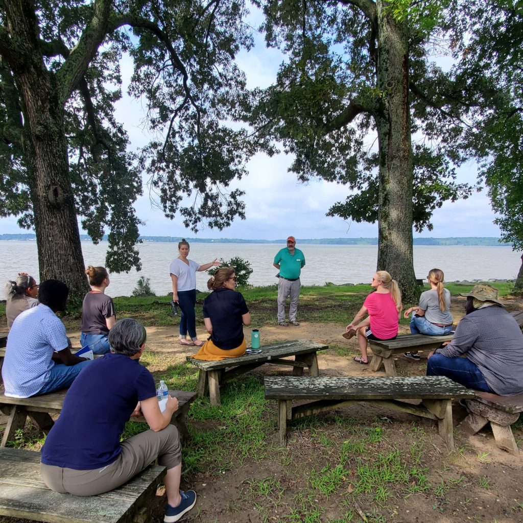 Leah and Mark stand at the edge of the waterfront and introduce DAACS attendees to the history of Jamestown.