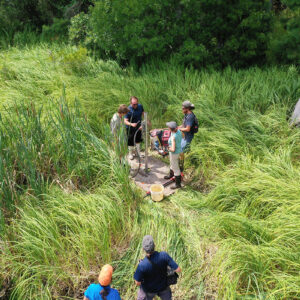 TerraSearch Geophysical's Dr. David Leslie demonstrates the vibracoring process to field school students Connor DeWall and Kristin Grossi with help from Archaeological Field Technician Josh Barber.