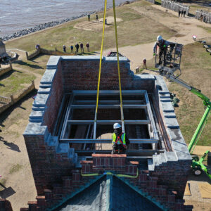 Two workers carefully guide the steel roof infrastructure inside the Church Tower.