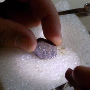 Hand holding coin under microscope